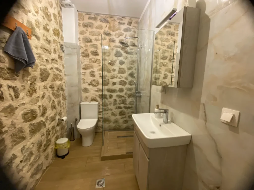 Το μπάνιο του Tsagariko Rooms με πέτρινο τοίχο